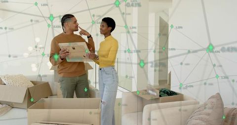 Couple unpacking boxes in modern living room holding tablet with augmented reality overlay