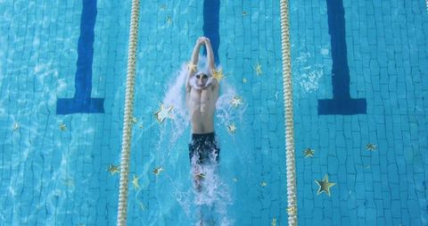 Male swimmer performing backstroke in turquoise pool between lane ropes with gold stars