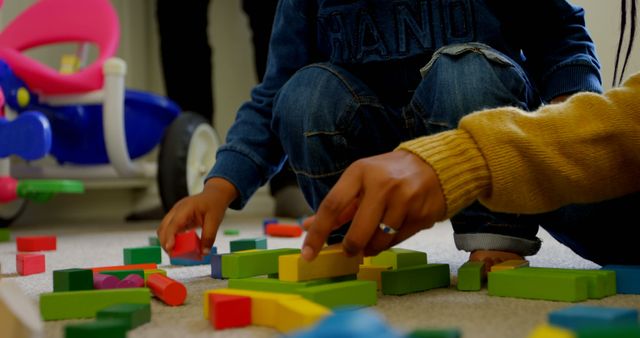 Close-up of young black family playing and sitting on floor of comfortable home. They are playing with building blocks 4k