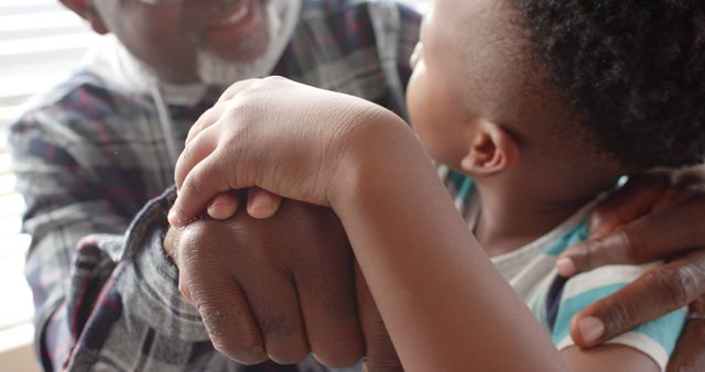Grandparent and child holding hands, emphasizing love and family bond. Useful for themes of support, affection, family connection, mentoring, and intergenerational relationships.
