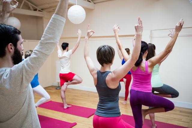 Group of individuals practicing gyan mudra yoga pose in a fitness studio. Ideal for promoting wellness, healthy lifestyle, and physical fitness. Useful for articles on yoga, group exercise classes, and mindfulness practices.