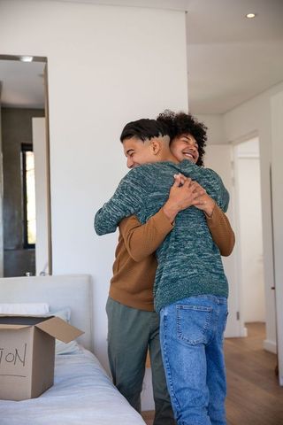 Father and Son Warm Embrace in Cozy Bedroom with Cardboard Box