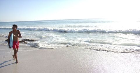 Young man surfing enthusiast enjoying sunny beach day