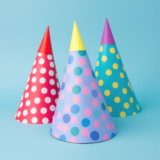 Colorful, polka-dotted party hats showcased on a blue background capture the festive atmosphere. Ideal for advertisements, social media posts, greeting cards, and party supply promos. Their vibrant colors and playful design make them perfect for events like birthdays, children's parties, and other joyous occasions.