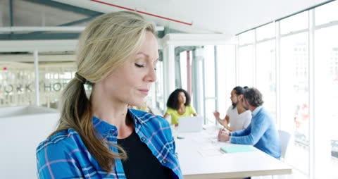 Smiling Professional Woman in Open Plan Office with Colleagues