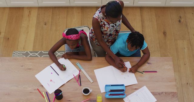 Overhead view of african american mother helping her daughter and son with homework at home. family, togetherness and happiness concept