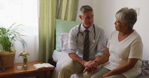 Senior Woman Sitting with Doctor Visiting at Home, Discussing Health Matters