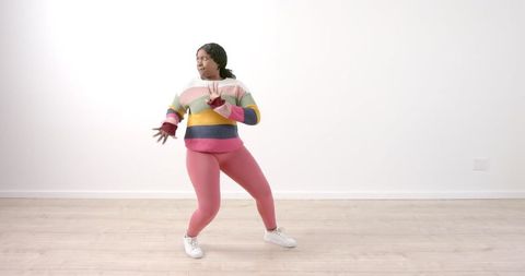 Woman Dancing Energetically in Colorful Sweater in Living Room