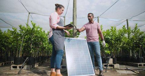 Diverse team analyzing solar panel at nursery for sustainable practices