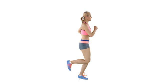 A young Caucasian woman is jogging in place, wearing athletic wear and sneakers, with copy space. Her active posture and attire suggest a focus on fitness and health.