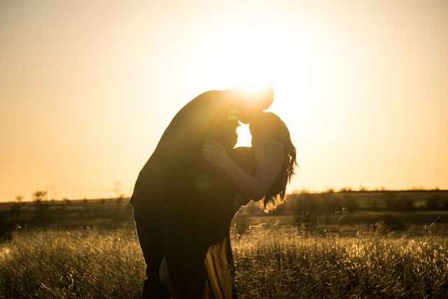 Couple Silhouetted at Sunset Kissing in Field - Download Free Stock Photos Pikwizard.com