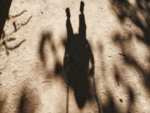 Shadow of couple holding hands on sandy path
