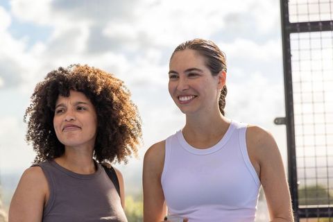 Two friends standing on rooftop in activewear holding water bottle urban fitness lifestyle
