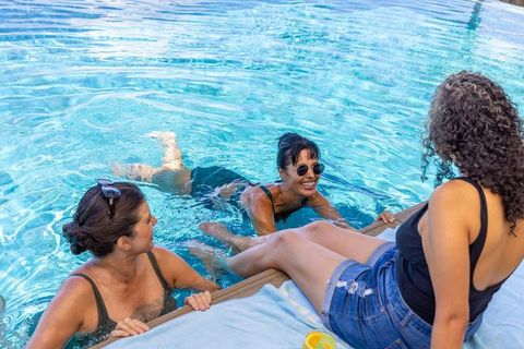 Diverse women relaxing and chatting poolside wearing swimwear and denim shorts