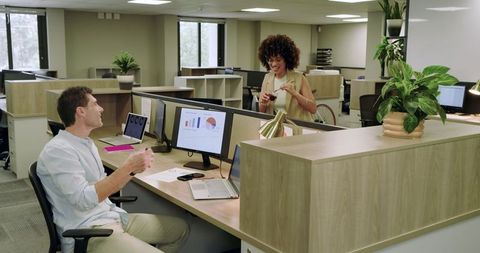 Coworkers Discussing Analytics with Coffee in Modern Office