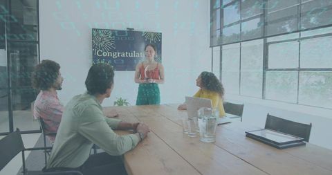 Young woman presenting Congratulations slide to team during bright boardroom celebration