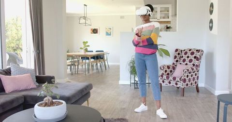Young woman experiencing virtual reality at home in casual attire