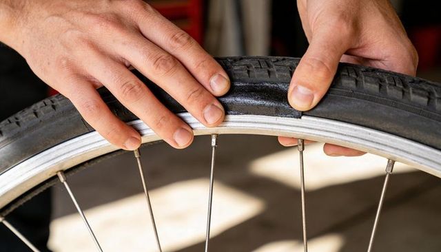 Hands applying patch to bicycle tire for fast tube repair and wheel maintenance