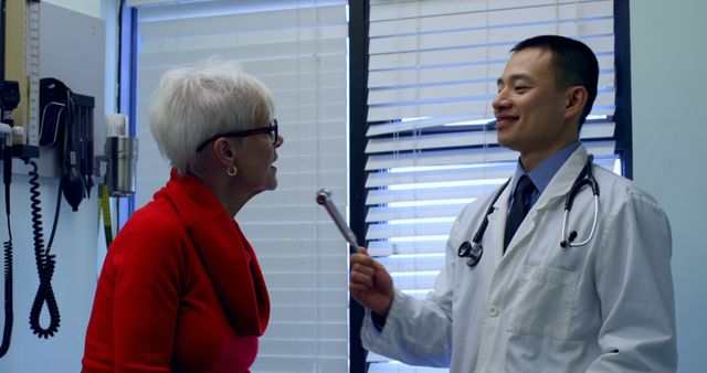 Doctor assessing neurological responses of a senior woman using a reflex hammer. Suitable for illustrating healthcare services, senior care, medical consultations, routine health examinations, and professional doctor-patient interactions.