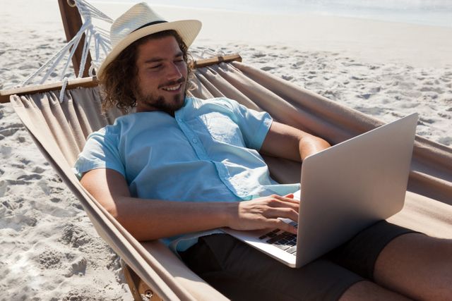 Man relaxing on hammock and using laptop on the beach - Download Free Stock Photos Pikwizard.com