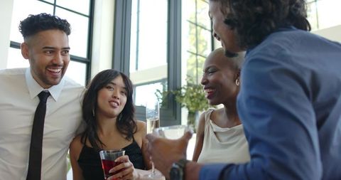 Diverse young professionals celebrating and clinking glasses in bright modern reception
