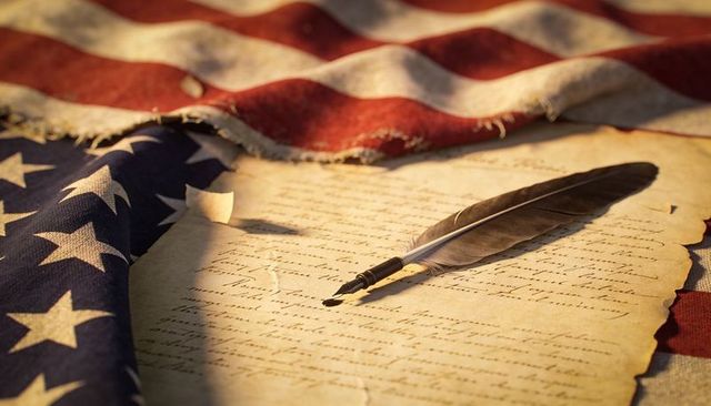 American heritage quill on aged parchment with worn flag evoking founding era patriotism
