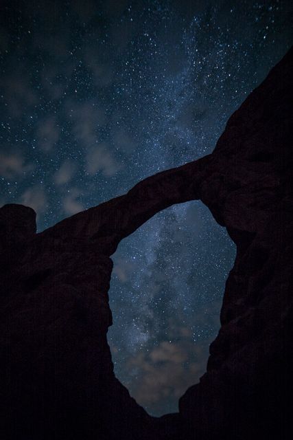 Natural rock arch silhouetted against a starry night sky showcasing the Milky Way. Ideal for use in themes related to nature, astronomy, night sky photography, geology, and outdoor adventures. This image captures the serene majesty of the natural landscape under the vastness of the cosmos.