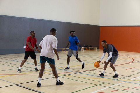 Friends playing pickup basketball indoors dribbling and defending on hardwood gym court