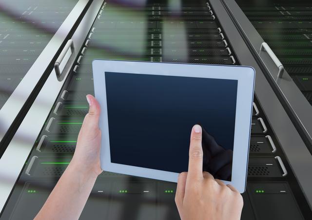 Hands holding and using digital tablet in front of server racks with green LED lights in a modern data center. Suitable for illustrating concepts of technology, IT maintenance, network management, data center operations, and server management.