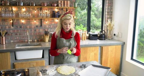 Holiday Baker Pressing Cookie Cutter into Dough on Rustic Kitchen Countertop