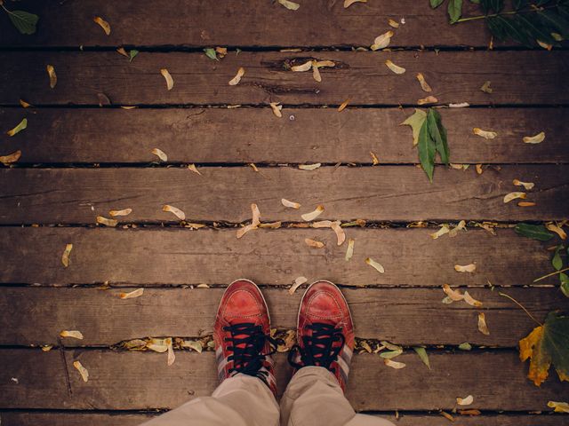 Worn Red Sneakers on Wooden Deck with Falling Leaves - Download Free Stock Photos Pikwizard.com