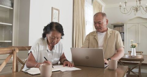 Asian Senior Couple Collaborating in Home Office Environment