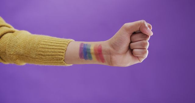 Hand of biracial man with lgbt flag on arm on purple background. Spending quality time at home.