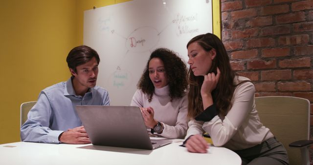 Caucasian professional businessman, biracial and Caucasian businesswomen working in a modern office together using laptop computer, brainstorming. Business creativity technology.