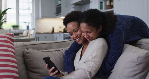 Couple Embracing on Couch Using Smartphone