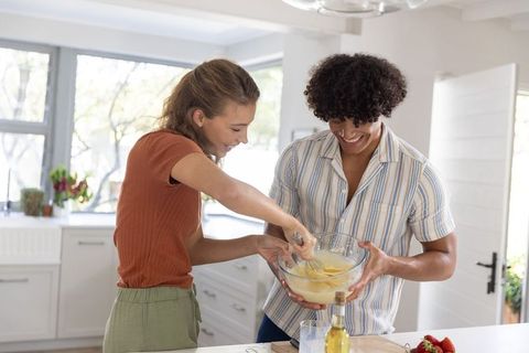 Young couple mixing batter at kitchen island sharing laughs and baking together