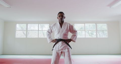 Confident teenage judoka posing in gym wearing white judogi