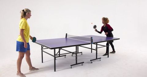 Women Engaged in Competitive Table Tennis Match Indoors