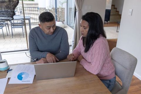 Senior couple discussing financial planning at home with laptop