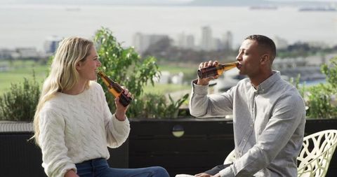 Friends enjoying beer on rooftop terrace with scenic view