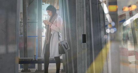 Asian Woman in Hijab Engaging with Smartphone in Urban Environment - Download Free Stock Images Pikwizard.com