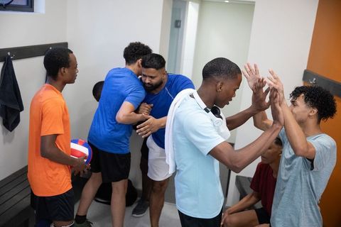 Diverse young volleyball team celebrating victory and camaraderie in locker room after match