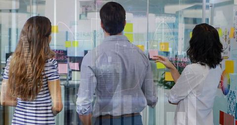 Collaborative team brainstorming ideas with concepts on glass wall