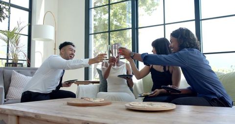 Friends toasting champagne in modern living room during semiformal celebration