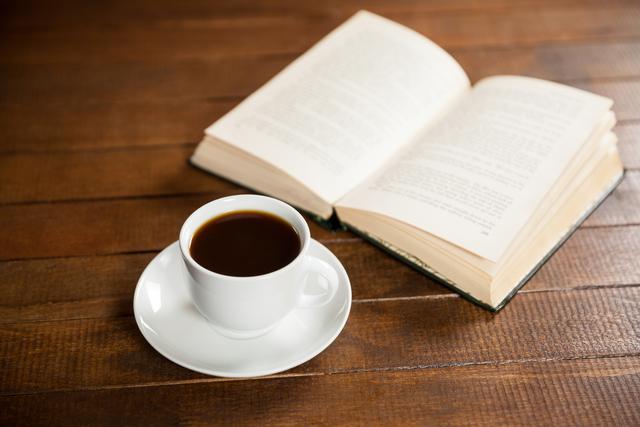 Close-up of coffee cup and book on wooden table