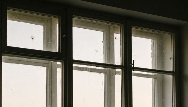 Weathered Multi-Pane Wooden Window with Dusty Glass and Metal Latch