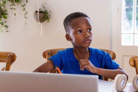 African american boy studying at home on laptop focusing on homework and remote learning