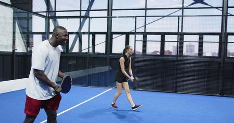 Diverse Friends Enjoying Padel Game on Modern Indoor Blue Court