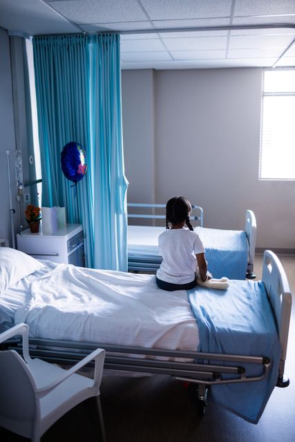 Rear view of patient sitting on bed in hospital