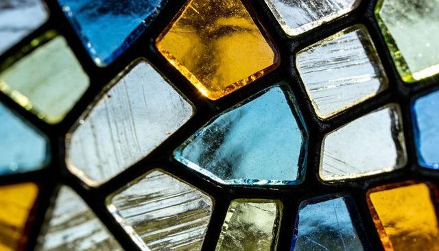Backlit stained glass mosaic panel with colorful geometric glass pieces and textured lead came